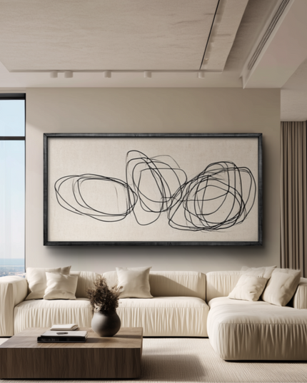 Modern living room with a beige sofa, abstract artwork, and large windows.