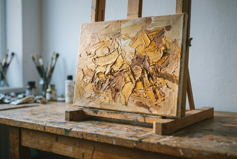 A heavily textured oil painting on a wood table, impasto ridges catching the low June morning light in the atelier