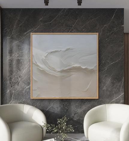 Modern living room with two white armchairs and a abstract painting on a marble wall.