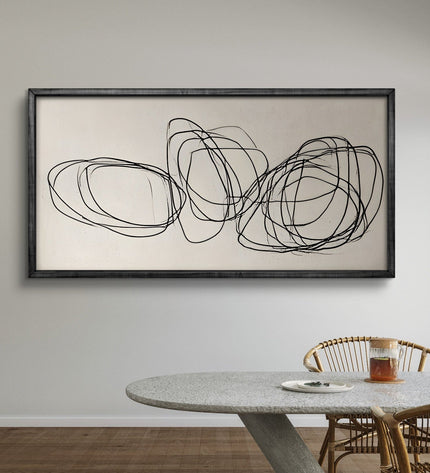 Abstract wall art with black lines on a beige background in a dining room setting.