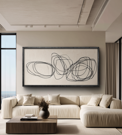 Modern living room with a beige sofa, abstract artwork, and large windows.